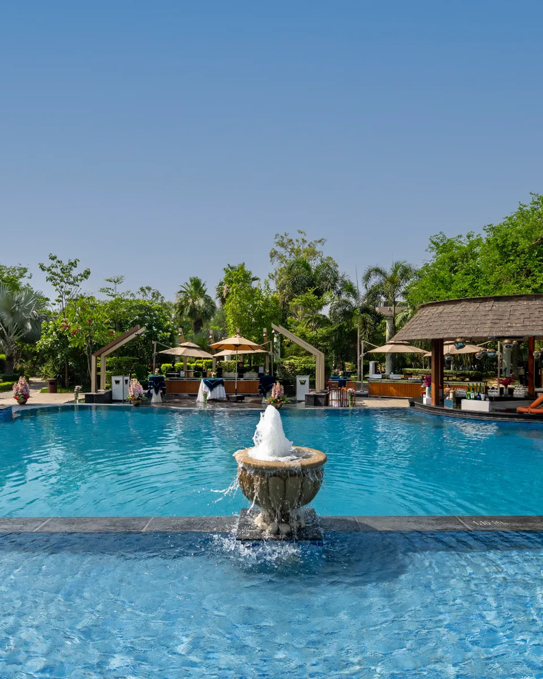 Swimming pool surrounded by greenery at City Park Green Resort, New Delhi